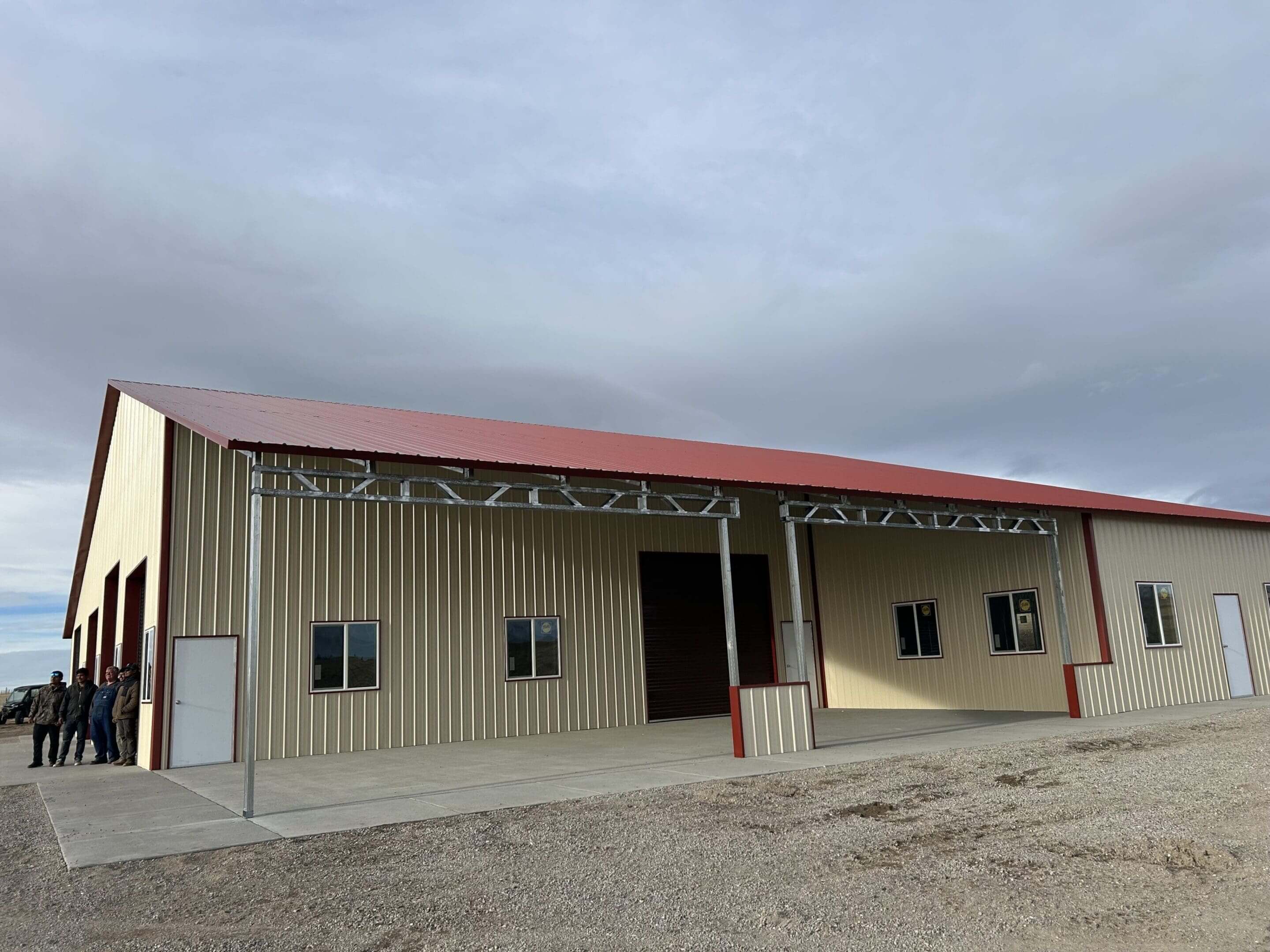 Metal building with red roof and sky.