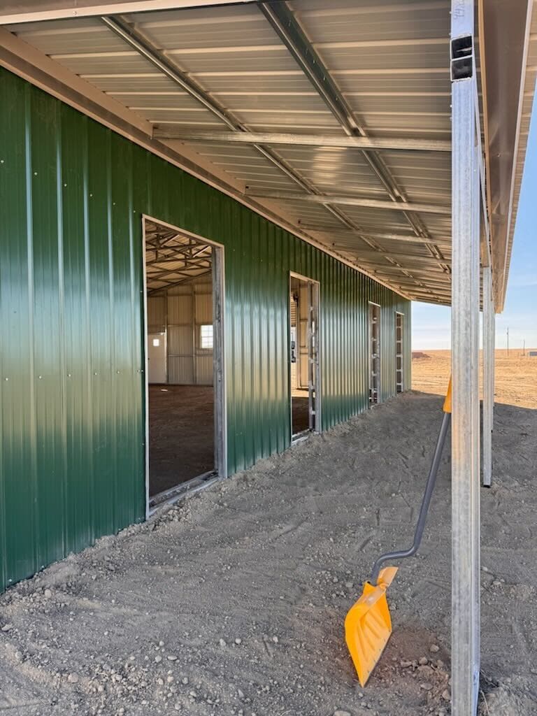Green metal building with open doorways.