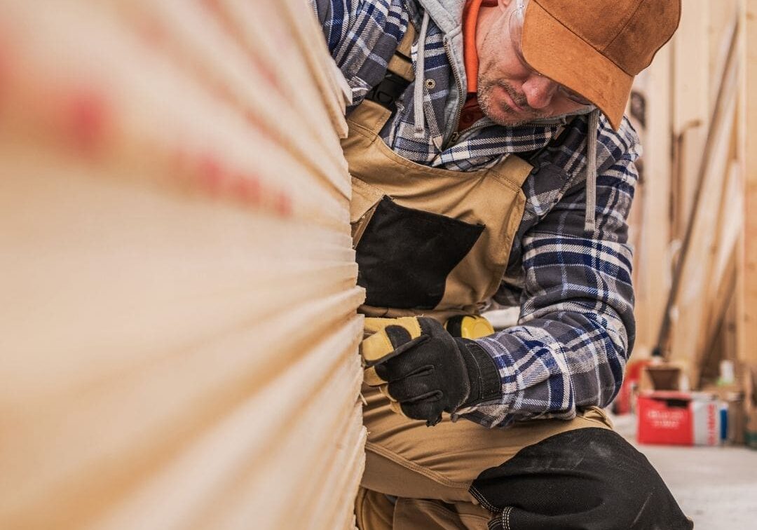 Carpenter measuring wooden plank in workshop.